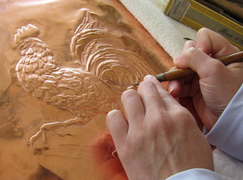 Artist embossing a sheet of copper