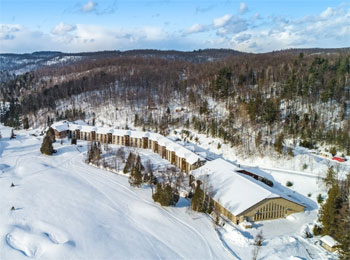 Aerial view of the hotel, surrounded by snow-covered fields and leafless trees.