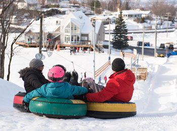 A family tubing down a snowy hill