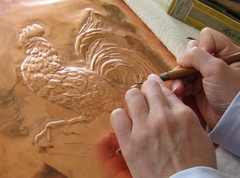 Artist embossing a sheet of copper