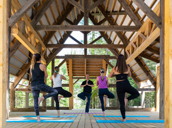 outdoor yoga class under a wooden roof at Le Baluchon Éco-villégiature