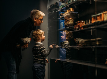 Young boy and grandparent looking at a model train exhibit
