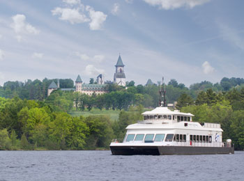 Cruise ship on a lake. There is an abbey in the background.
