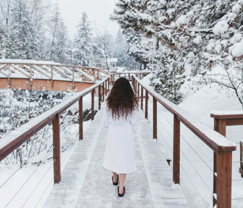 Woman walking toward bridge in winter at Strøm Nordic Spa Saint-Sauveur