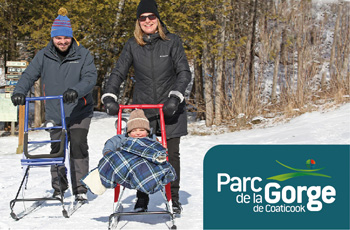 Two parents and their child exploring the trails on a snow scooter