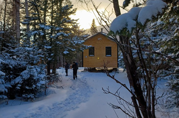 Two hikers outside a cabin in the wilderness