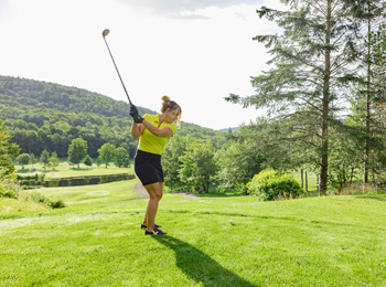 Woman on a golf course about to hit the ball.