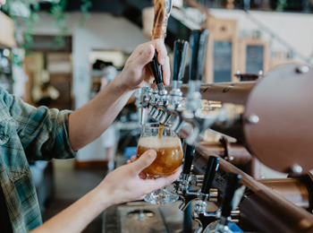 Un barman rempli un verre de bière à la pression.