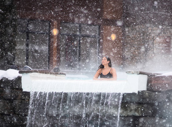 Woman in a thermal pool under the snowflakes