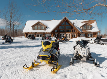 Two snowmobiles in front of a lodge