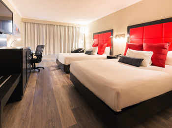Interior of a red-accented hotel room with two queen-size beds